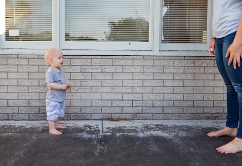 Toddler in a stand off with mum outside home - Australian Stock Image