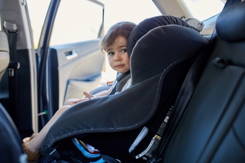 Toddler in child car seat staring at camera - Australian Stock Image