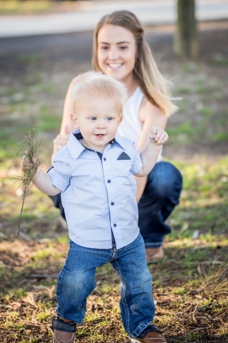 Toddler learning to walk with mum watching - Australian Stock Image