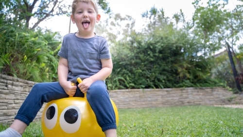 Toddler on jumping ball in backyard - Australian Stock Image