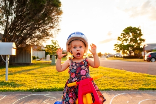 Toddler on trike with open mouthed shock expression wearing helmet - Australian Stock Image