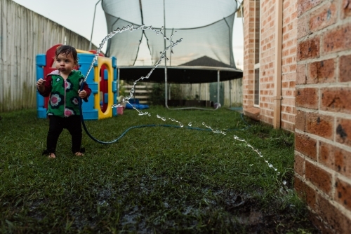 Toddler with hose outside
