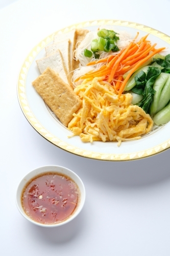 Tofu and egg noodle salad served in a bowl with a gold rim. - Australian Stock Image