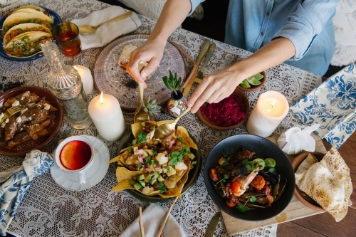 Top-down view of a table with various dishes and people eating. - Australian Stock Image