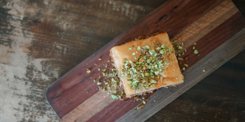 Top down view of Baklava on wooden board with chopped pistachios. Banner with copy space. - Australian Stock Image