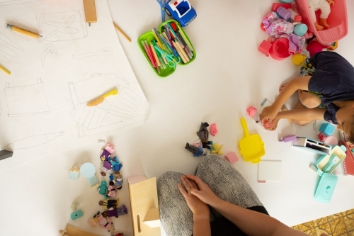 top down view of occupational therapist sitting on floor with child playing with toys - Australian Stock Image