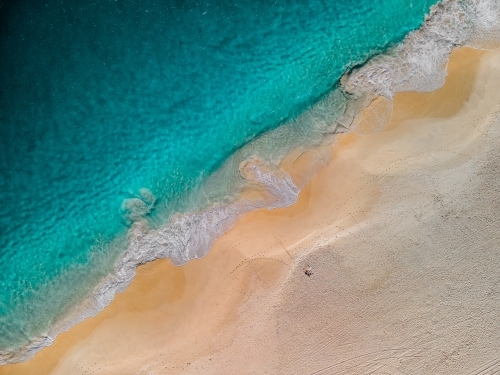 top shot of a beach with a white sand shore and sea waves on a sunny day - Australian Stock Image