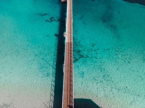 top shot of a beach with a wooden walkway and white sand shoreline on a sunny day - Australian Stock Image