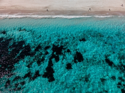 top shot of a beach with waves, seaweeds and people on a sunny day - Australian Stock Image