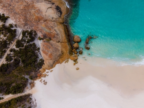 top shot of a beach with white sand shoreline, waves, bushes, trees and rocks - Australian Stock Image