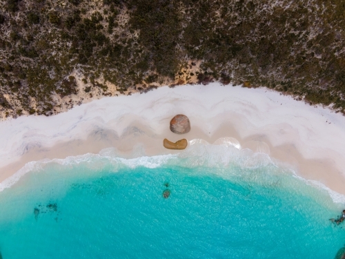 top shot of a beach with white sand shoreline, waves, bushes, trees and rocks - Australian Stock Image