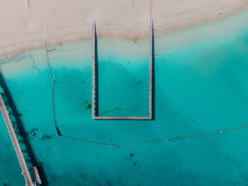 top shot of a beach with wooden walkways and white sand shoreline on a sunny day - Australian Stock Image