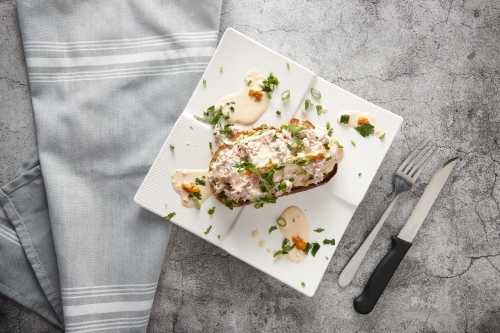 top shot of avocado tuna toast with bread knife and fork on the side - Australian Stock Image