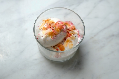 Top shot of home made coconut icecream with nuts and pink sprinklers - Australian Stock Image