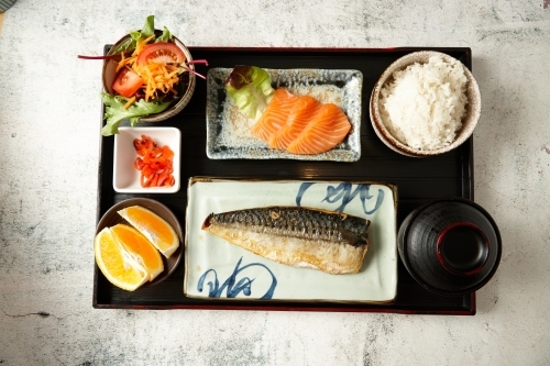 top shot of salmon cuts, fried fish, rice and side dishes - Australian Stock Image