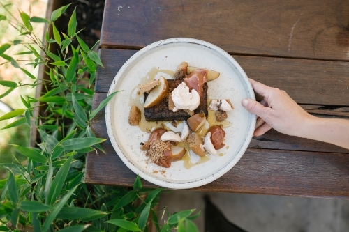 Top view of a dessert on a round plate served on a wooden table - Australian Stock Image