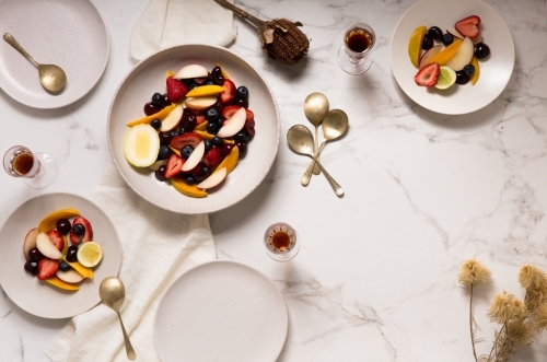 Top view of mixed stone fruit salad brunch with guests on light background