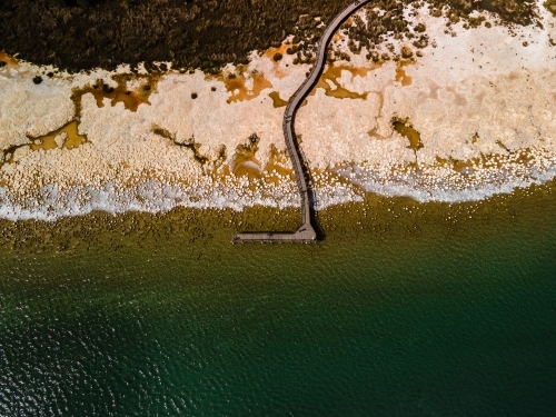 top view shot of a beach walkway with bushes, trees and waves on a sunny day - Australian Stock Image
