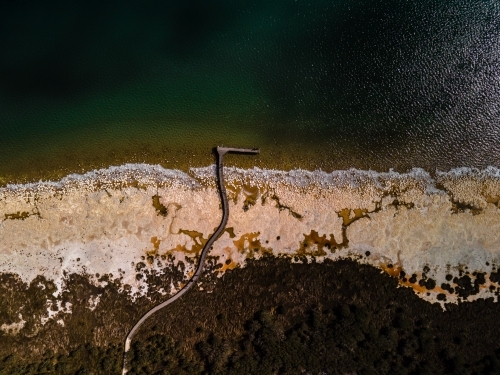 top view shot of a beach walkway with bushes, trees and waves on a sunny day - Australian Stock Image