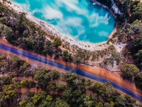 top view shot of blue lake with a sky reflection, with green trees and a road - Australian Stock Image