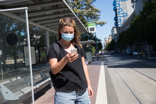 Tourist Wearing Face Mask Waiting for the Tram - Australian Stock Image