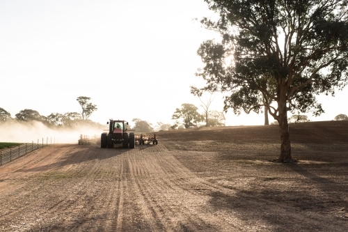 Tractor cultivating the field on a sunny day dust rising