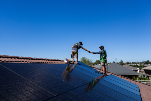 Tradesman electrician workers working together installing solar power bifacial panel system - Australian Stock Image