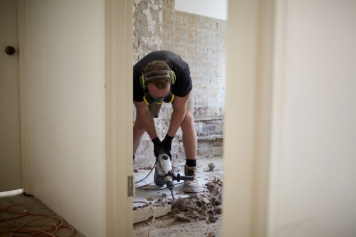 Tradesman jackhammering a floor in a home renovation - Australian Stock Image