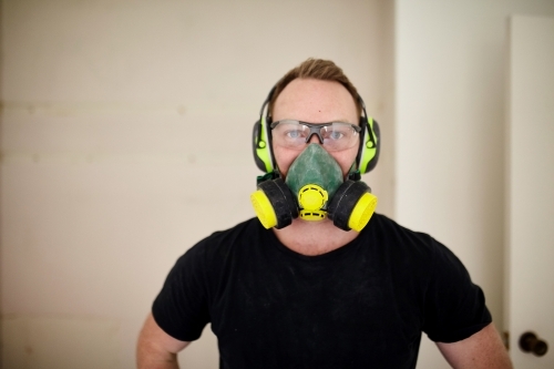 Tradesman standing in a room in a construction zone wearing protective equipment - Australian Stock Image