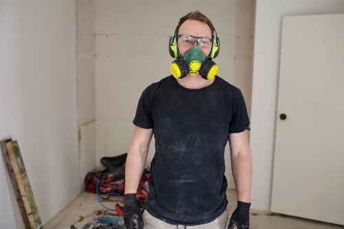 Tradesman standing in a room in a construction zone wearing protective equipment