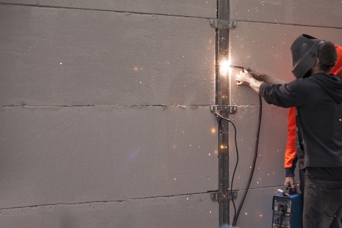 Tradesman welding fencing in a home environment - Australian Stock Image