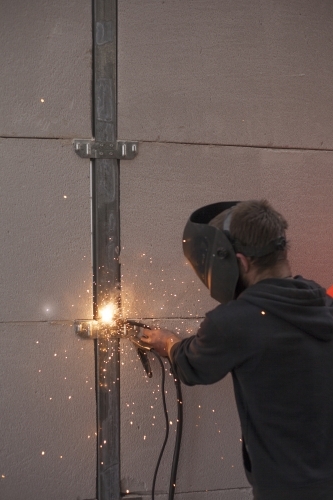 Tradesman welding fencing in a home environment