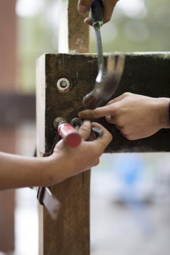 Tradesmen attaching a washer to secure a bolt to a wooden beam. - Australian Stock Image