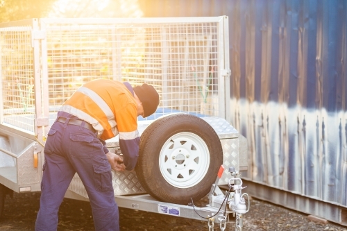 Tradie in golden light opening up lock box on trailer - Australian Stock Image