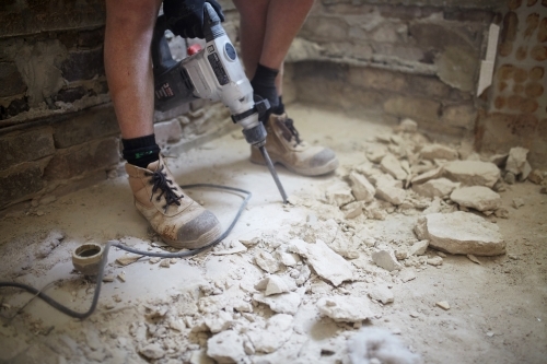 Tradie jackhammering a floor in a dusty worksite - Australian Stock Image