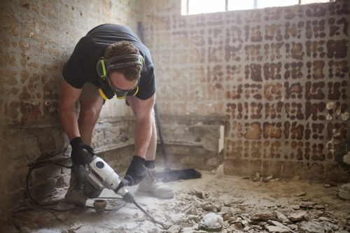 Tradie jackhammering a floor in a renovation site - Australian Stock Image