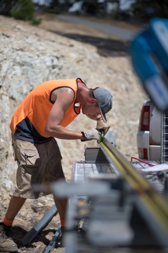 Tradie measuring metal frame on construction site - Australian Stock Image