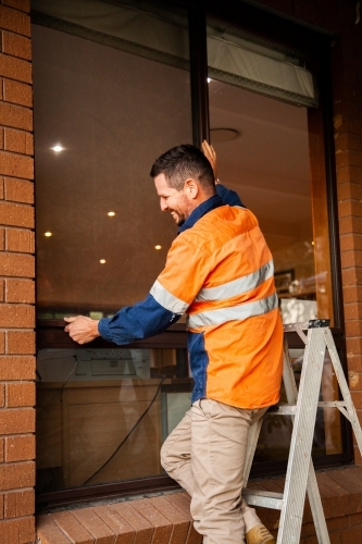 Tradie replacing screen of home window - Australian Stock Image