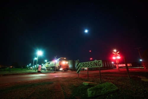 Train passing rail crossing at night.