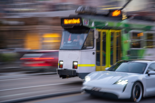 Tram and car rushing along a city street in Melbourne - Australian Stock Image