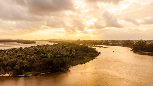 tranquil river estuary winding through vibrant green landscape at golden hour - Australian Stock Image