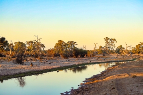Tranquil small creek running through remote rural property at sunset - Australian Stock Image