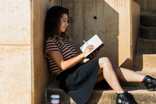 traveller writing in diary by the ocean - Australian Stock Image