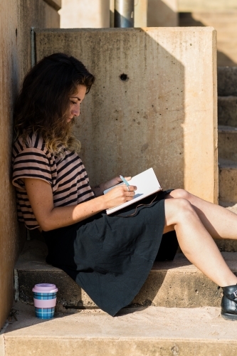 traveller writing in diary by the ocean - Australian Stock Image