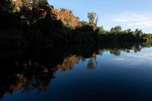 Trees by the river with its shadow reflecting on it. - Australian Stock Image