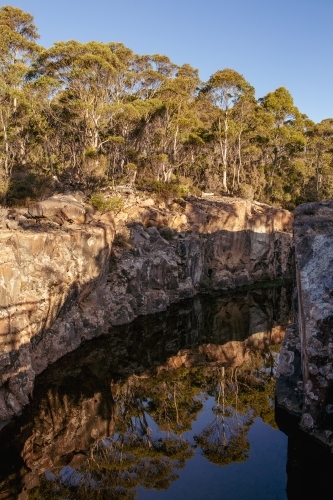 Trees reflected in creek bed, afternoon sun - Australian Stock Image
