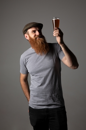 Trendy guy holding a glass of beer, relaxed and happy