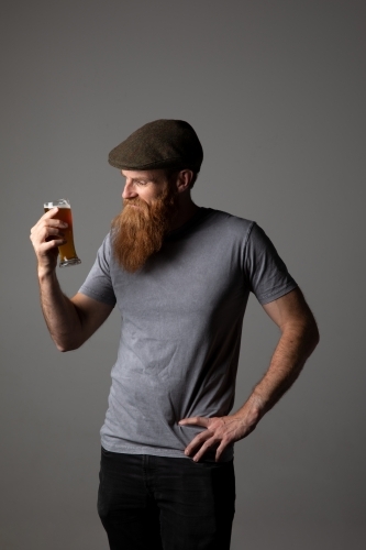 Trendy guy holding a glass of beer, relaxed and happy - Australian Stock Image