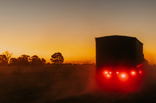 Truck driving into dusty sunset - Australian Stock Image