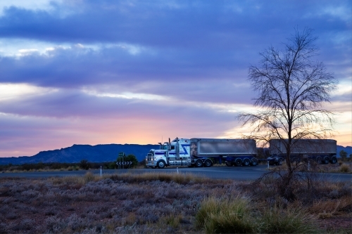 Truck travelling through remote location at dawn - Australian Stock Image